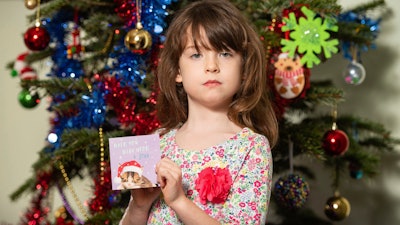 Florence Widdicombe, 6, poses with a Tesco Christmas card from the same pack as a card she found containing a message from a Chinese prisoner, in London, Sunday, Dec. 22, 2019. The U.K.-based grocery chain Tesco has halted production at a factory in China after a British newspaper said it used forced labor to produce charity Christmas cards. Tesco said Sunday it had stopped production and launched an investigation after the Sunday Times newspaper raised questions about the factory's labor practices.