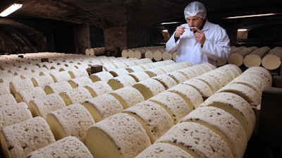 In this Jan. 21, 2009, file photo, Bernard Roques, a refiner of Societe company, smells a Roquefort cheese as they mature in a cellar in Roquefort, southwestern France. The Trump administration is proposing tariffs on up to $2.4 billion worth of French imports, from Roquefort cheese to handbags, retaliation for France’s tax on American tech giants like Google, Amazon and Facebook. The Office of the U.S. Trade Representative says France’s new digital services tax discriminates against U.S. companies and says that the tariffs could reach 100%.