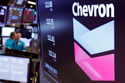 This Oct. 8, 2019, file photo shows the logo for Chevron on the floor of the New York Stock Exchange. Chevron Corp. reports financial results Friday, Nov. 1. Chevron said Tuesday, Dec. 10, it will book a charge of at least $10 billion because lower long-term prices for oil and natural gas are making some projects less valuable.