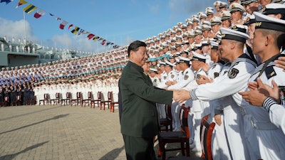 In this photo provided by China's Xinhua News Agency, Chinese President Xi Jinping, center, meets with representatives of the aircraft carrier unit and the manufacturer at a naval port in Sanya, south China's Hainan Province, Tuesday, Dec. 17, 2019. President Xi attended the commissioning of China’s first entirely home-built aircraft carrier, underscoring the country's rise as a regional naval power at a time of tensions with the U.S. and others over trade, Taiwan and the South China Sea.