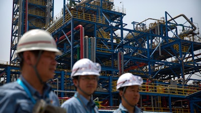 In this May 25, 2018, file photo, workers stand near facilities for producing polypropylene at the Sinopec Yanshan Petrochemical Company on the outskirts of Beijing. China's government promised Monday to open its oil, telecom and power markets wider to private competitors as the ruling Communist Party tries to shore up growth in the slowing, state-dominated economy.