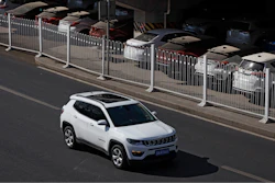 In this March 14, 2019, file photo, an SUV moves past dust-covered new Toyota cars stored underneath an overpass in Beijing. China's auto sales sank 5.4% in November from a year ago, putting the industry's biggest global market on track to shrink for a second year, an industry group reported Tues, Dec. 10, 2019. Drivers bought just over 2 million SUVs, sedans and minivans, according to the China Association of Automobile Manufacturers.