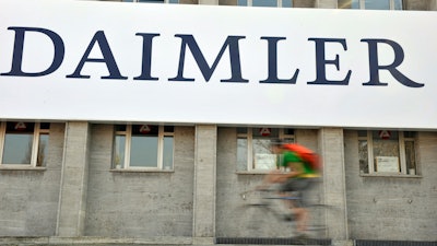 In this April 8, 2009 file photo, a cyclist passes a logo of German car company Daimler in Berlin. German automaker Daimler said Friday, Nov. 29, 2019 that it plans to cut at least 10,000 jobs worldwide by the end of 2022. The company had said Nov. 14 that it plans to slash costs by 1.4 billion euros ($1.54 billion) by cutting every tenth managerial position and through other measures, but didn’t give details.