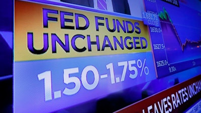 A television screen on the floor of the New York Stock Exchange shows the rate decision of the Federal Reserve, Wednesday, Dec. 11, 2019. The Federal Reserve is leaving its benchmark interest rate alone and signaling that it expects to keep low rates unchanged through next year.