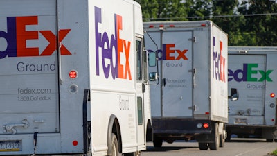 In this June 26, 2019, file photo delivery vehicles depart the FedEx Ship Center in Cranberry Township, Pa. FedEx reports earnings Tuesday, Dec. 17.
