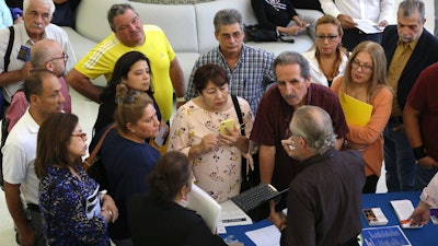 In this Sept. 18, 2019, file photo people inquire about temporary positions available for the 2020 Census during a job fair designed for people fifty years or older in Miami. On Friday, Dec. 6, the U.S. government issues the November jobs report.