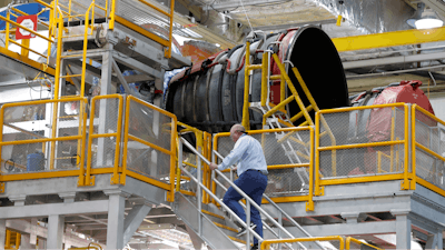 An employee walks up to two of the four rocket engines of NASA's Space Launch System (SLS) as the Artemis 1 rocket core stage is assembled at the NASA Michoud Assembly Center in New Orleans, Monday, Dec. 9, 2019.