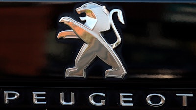 In this Oct. 31, 2019, file photo, a Peugeot logo pictured on a car in Bayonne, southwestern France. Fiat Chrysler Automobiles and PSA Peugeot announced Wednesday, Dec. 18, 2019, that their boards signed a binding deal to merge the two automakers, creating the world’s fourth-largest auto company.