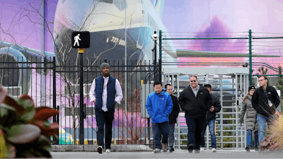 Boeing workers exit the plant in front of a giant mural of a jet on the side of the manufacturing building behind Monday, Dec. 16, 2019, in Renton, Wash. Shares of Boeing fell before the opening bell on a report that the company may cut production of its troubled 737 MAX or even end production all together.