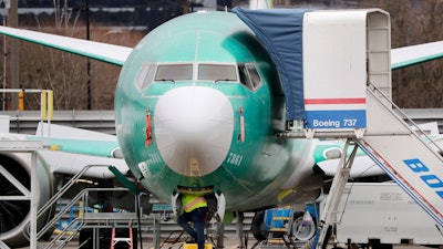A worker looks up underneath a Boeing 737 MAX jet Monday, Dec. 16, 2019, in Renton, Wash. Shares of Boeing fell before the opening bell on a report that the company may cut production of its troubled 737 MAX or even end production all together.