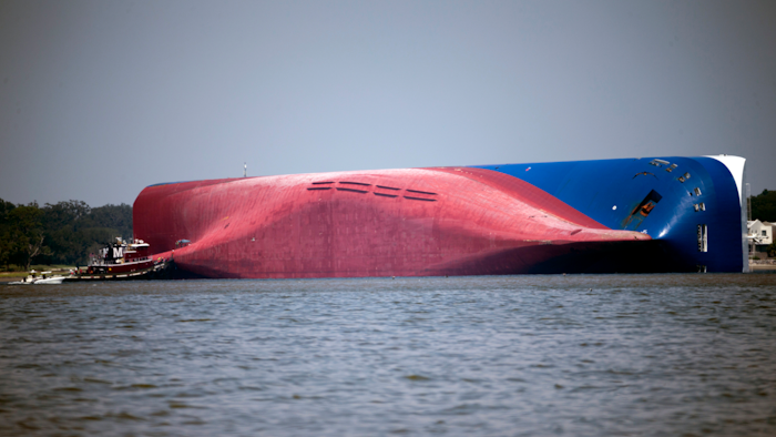 In this Sept. 9, 2019, file photo, a Moran tugboat nears the stern of the capsizing vessel Golden Ray as a tent and rescuers can be seen near the bottom of the ship near the tug boat in Jekyll Island, Ga. A Texas-based salvage company will cut up and remove the 656-foot (200- meter) shipwreck from St. Simons Sound off the coast of Georgia. The Coast Guard's Unified Command has hired T&T Salvage LLC of Galveston to remove the Golden Ray cargo ship, The Brunswick News reported. The ship, roughly the size of a 70-story office building, has sat overturned in the sound for four months.