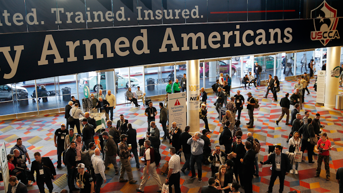 In this Wednesday, Jan. 24, 2018, file photo, people walk through the hall outside of the SHOT Show gun show in Las Vegas.