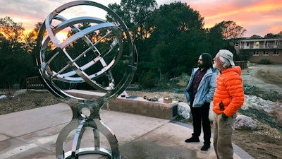 In this Dec. 11, 2019 photo Bill Donahue, right, a retired teacher and director of laboratories at St. John's College, and student Devin Ketch use an armillary sphere to track planetary rotations and explore the history of astronomy in Santa Fe, N.M. The unique precision-steel replica of an instrument created by Danish astonomer Tycho Brahe was commissioned by graduates of the college where students trace the evolution of math and science from early civilizations.