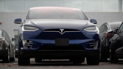 In this Oct. 20, 2019, photo an unsold 2019 Model X sits under a sign at a Tesla dealership in Littleton, Colo. Tesla says its global deliveries rose more than 50% last year meaning the company surpassed the low end of its sales goals for 2019. The electric car maker said Friday, Jan. 3, 2020, that it delivered a record of about 112,000 vehicles in the fourth quarter and about 367,500 for the full year. Tesla previously announced that it expected to deliver 360,000 to 400,000 units worldwide last year.