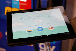 An employee holds a tablet showing a video demonstrating the Alexa pay for gas feature in the Amazon booth at the CES tech show, Wednesday, Jan. 8, 2020, in Las Vegas.