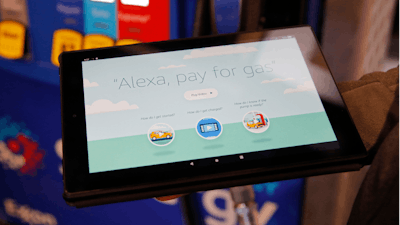 An employee holds a tablet showing a video demonstrating the Alexa pay for gas feature in the Amazon booth at the CES tech show, Wednesday, Jan. 8, 2020, in Las Vegas.