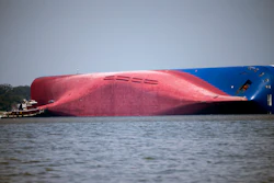 In this Sept. 9, 2019, file photo, a Moran tugboat nears the stern of the capsizing vessel Golden Ray as a tent and rescuers can be seen near the bottom of the ship near the tug boat in Jekyll Island, Ga. A Texas-based salvage company will cut up and remove the 656-foot (200- meter) shipwreck from St. Simons Sound off the coast of Georgia. The Coast Guard's Unified Command has hired T&T Salvage LLC of Galveston to remove the Golden Ray cargo ship, The Brunswick News reported. The ship, roughly the size of a 70-story office building, has sat overturned in the sound for four months.