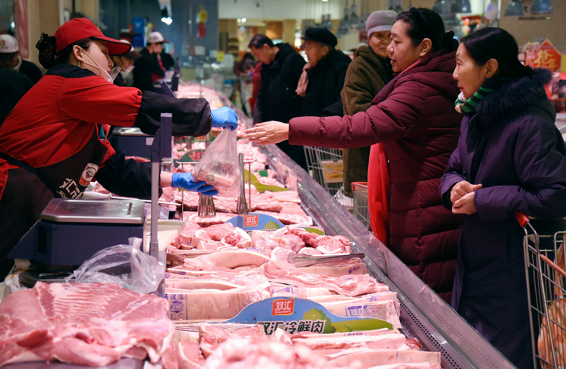 People shop for meat a supermarket in Handan in northern China's Hebei Province, Thursday, Jan. 9, 2020. Soaring pork prices that nearly doubled in December over a year ago kept inflation at a seven-year high despite government efforts to ease meat shortages caused by a disease outbreak, official data showed Thursday.