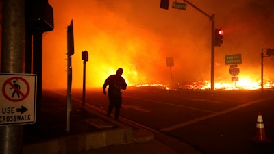 In this Oct. 11, 2019 file photo, a bystander watches the Saddleridge Fire in Sylmar, Calif. A state lawmaker is demanding an extensive review of the California Public Utilities Commission to determine whether regulators' lax oversight enabled the neglectful behavior at Pacific Gas & Electric that triggered catastrophic wildfires, a messy bankruptcy and exasperating blackouts.