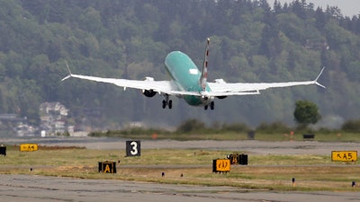 In this May 8, 2019, file photo a Boeing 737 MAX 8, being built for American Airlines, is partially obscured by the engine wash as it takes-off on a test flight in Renton, Wash. A government committee reviewing how the Federal Aviation Administration certifies new passenger planes for flight has determined that the system is safe and effective but small changes need to be made. The committee was appointed by Transportation Secretary Elaine Chao in April after two deadly crashes involving Boeing's 737 Max.