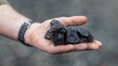 In this Tuesday, Jan. 14, 2020, photo, Dusty Maynard, an employee of Quest Energy, holds pieces of coal found on the ground near railroad tracks where miners, who say they haven't been paid in nearly three weeks, block a coal train in the Kimper area of Pike County, Ky. A group of Kentucky coal miners who blocked a railroad track for three days over unpaid wages have ended their protest, claiming victory with their paychecks.