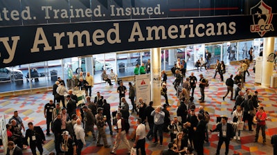 In this Wednesday, Jan. 24, 2018, file photo, people walk through the hall outside of the SHOT Show gun show in Las Vegas.