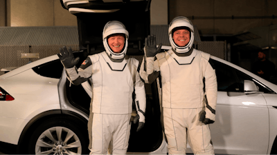 In this Friday, Jan. 17, 2020, photo provided by NASA, astronauts Doug Hurley, left, and Robert Behnken pose in front of a Tesla Model X at a SpaceX launch dress rehearsal, at Kennedy Space Center, in Florida. The NASA astronauts rode to the pad in the Tesla.