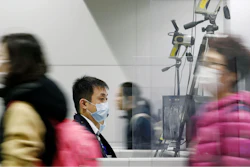 Passengers wearing masks walk by as a quarantine officer, center, monitors a thermography during a quarantine inspection at Kansai international airport in Osaka, western Japan, Wednesday, Jan. 22, 2020.