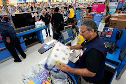 In this Nov. 9, 2018, file photo Walmart associate Javaid Vohar, right, checks out customers at a Walmart Supercenter in Houston. Walmart says it is testing higher wages for new hourly positions at 500 of its U.S. stores as part of an overall strategy to better empower its staff.