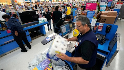 In this Nov. 9, 2018, file photo Walmart associate Javaid Vohar, right, checks out customers at a Walmart Supercenter in Houston. Walmart says it is testing higher wages for new hourly positions at 500 of its U.S. stores as part of an overall strategy to better empower its staff.