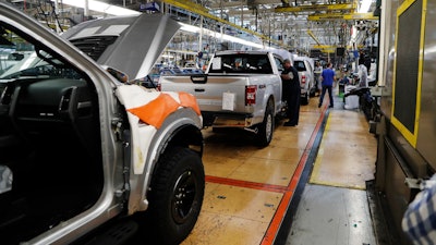 In this Sept. 27, 2018, file photo a United Auto Workers assemblyman works on a 2018 Ford F-150 truck being assembled at the Ford Rouge assembly plant in Dearborn, Mich. Ford is recalling its popular F-150 pickup truck in Canada to fix a problem with electric tailgate latches, but identical trucks aren't being recalled in the U.S.