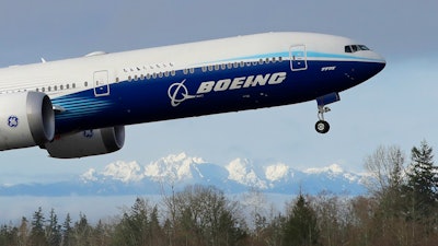 In this Jan. 25, 2020, file photo a Boeing 777X airplane takes off on its first flight with the Olympic Mountains in the background at Paine Field in Everett, Wash. Boeing Co. reports financial results on Wednesday, Jan. 29.