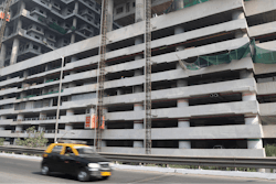 In this Tuesday, Jan. 21, 2020, file photo, a car drives past an under-construction building in Mumbai, India, Tuesday, Jan. 21, 2020. India’s government expects the economy to expand up to 6.5% in the next fiscal year, starting in April, and hopes to follow China's example in developing labor intensive industries and exports.