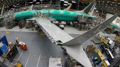 In this March 27, 2019, photo taken with a fish-eye lens, a Boeing 737 MAX 8 airplane sits on the assembly line during a brief media tour in Boeing's 737 assembly facility in Renton, Wash. The looming production shutdown of Boeing 737 Max jets is taking a toll on a key supplier. Spirit AeroSystems Holdings Inc. is asking employees if they will take voluntarily buyouts. Spirit suspended production of fuselages and other parts for the Max on Jan. 1, 2020, after Boeing told the Wichita, Kansas, company to suspend shipments.