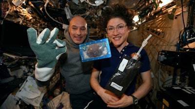 In this photo made available by U.S. astronaut Christina Koch via Twitter on Dec. 26, 2019, she and Italian astronaut Luca Parmitano pose for a photo with a cookie baked on the International Space Station. Researchers want to inspect the handful of chocolate chip cookies baked by astronauts in a special Zero G oven.