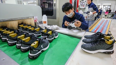 In this Jan. 3, 2020, photo, workers make sneakers in a factory in Jinjiang city in southeastern China's Fujian province. China’s economic growth sank to a new multi-decade low of 6.1% in 2019 as consumer demand weakened and Beijing fought a trade war with Washington. Government data Friday, Jan. 17, showed growth was down from 2018’s 6.6%, already the lowest since 1990. Economic growth in the three months ending in December held steady at the previous quarter’s level of 6%.
