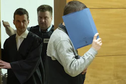 A 57-year old defendant hides his face at the courtroom in Bielefeld, Germany, Thursday, March 7, 2019. A judge in Germany has found the man guilty of poisoning his co-workers' sandwiches with mercury, lead acetate and other chemicals over several years and sentenced him to life in prison.