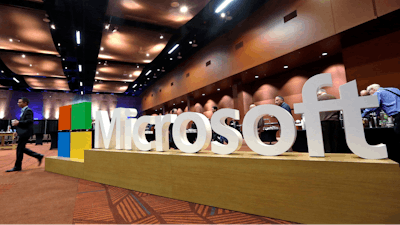 In this Nov. 30, 2016, file photo a man walks past a Microsoft sign at the annual Microsoft shareholders meeting in Bellevue, Wash. Microsoft on Thursday, Jan. 16, 2020, is announcing a plan to reduce its carbon footprint.