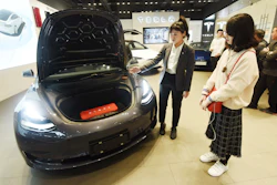 In this Nov. 24, 2019, photo, a saleswoman talks about a Tesla Model 3 car at a Tesla showroom in Hangzhou in eastern China's Zhejiang Province. Tesla's Shanghai factory delivered its first cars to customers Monday, Jan. 6, 2020, and chief executive Elon Musk said the electric automaker plans to set up a design center in China to create a model for worldwide sales.