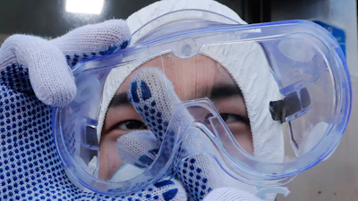 A worker cleans his goggles to spray disinfectant as a precaution against the coronavirus at a shopping street in Seoul, South Korea, Thursday, Feb. 27, 2020. South Korea and China each reported hundreds more virus cases Thursday as the new illness persists in the worst-hit areas and spreads beyond borders.