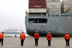 In this Tuesday, Feb. 4, 2020, photo, workers watch a container ship arrive at a port in Qingdao in east China's Shandong province.