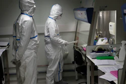 French lab scientists in hazmat gear inserting liquid in test tube manipulate potentially infected patient samples at Pasteur Institute in Paris, Thursday, Feb. 6, 2020. Scientists at the Pasteur Institute developed and shared a quick test for the new virus that is spreading worldwide, and are using genetic information about the coronavirus to develop a potential vaccine and treatments.