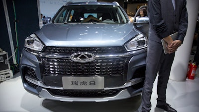 In this April 25, 2018, file photo a staff member stands next to a Tiggo 8 SUV by Chinese automaker Chery after a press conference at the China Auto Show in Beijing.