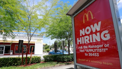 In this July 1, 2019, file photo, a help wanted sign appears on a bus stop in front of a McDonald's restaurant in Miami.
