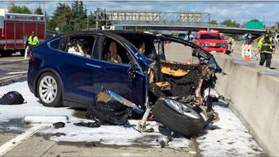 In this March 23, 2018, file photo provided by KTVU, emergency personnel work a the scene where a Tesla electric SUV crashed into a barrier on U.S. Highway 101 in Mountain View, Calif.