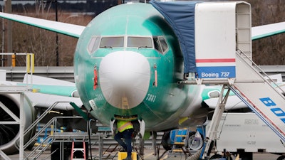 In this Dec. 16, 2019, file photo a worker looks up underneath a Boeing 737 MAX jet in Renton, Wash.
