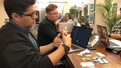 In this Monday, Jan. 13, 2020, photograph taken in Denver, software engineer David Viramontes, front, and digital strategist Patrick Collins direct a meeting of Code For Denver.