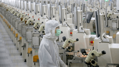 In this Feb. 20, 2020, photo, a worker sits at a production line at a microelectronics factory in Nantong in eastern China's Jiangsu Province. China on Friday suspended more punitive tariffs on imports of U.S. industrial goods in response to a truce in its trade war with Washington that threatened global economic growth.