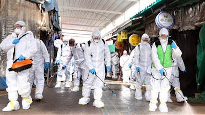 Workers wearing protective suits spray disinfectant as a precaution against the coronavirus at a market in Bupyeong, South Korea, Monday, Feb. 24, 2020. South Korea reported another large jump in new virus cases Monday a day after the the president called for 'unprecedented, powerful' steps to combat the outbreak that is increasingly confounding attempts to stop the spread.