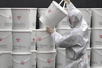 A worker in protective gear stacks plastic buckets containing medical waste from coronavirus patients at a medical center in Daegu, South Korea, Monday, Feb. 24, 2020. South Korea reported another large jump in new virus cases Monday a day after the the president called for 'unprecedented, powerful' steps to combat the outbreak that is increasingly confounding attempts to stop the spread.